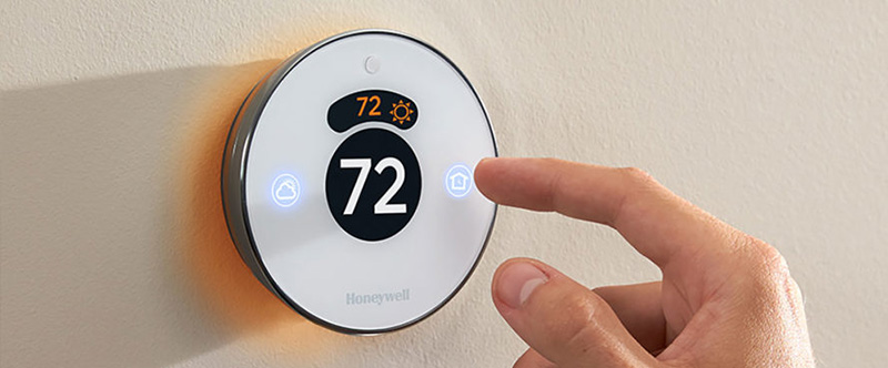 A hand adjusting the Honeywell thermostat